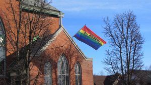 An LGBTQ pride flag waving outside of Emmanuel United Church.