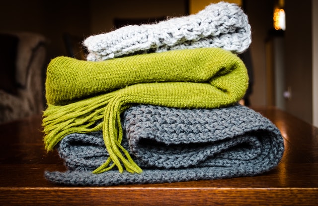 A stack of folded scarves and mittens.