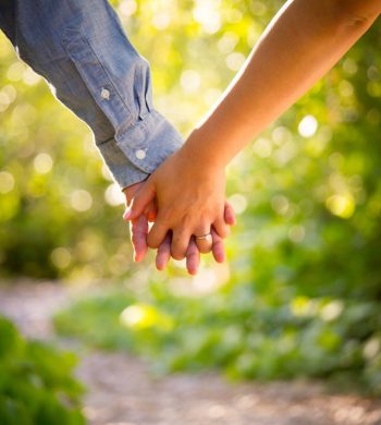 Two people holding hands in the forest.